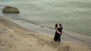 Deniz kenarında siyah giyim kucaklayan içinde çift