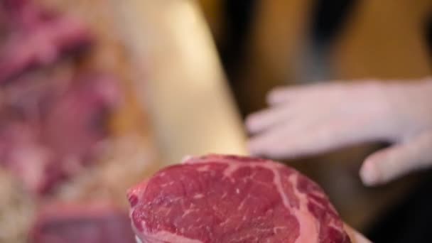 Шеф-повар в перчатках держит мясо для стейка — стоковое видео