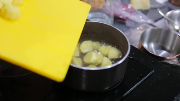 Повар наливает картошку в кипящую воду — стоковое видео