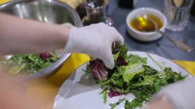 Şef salata bir tabağına koyuyor.