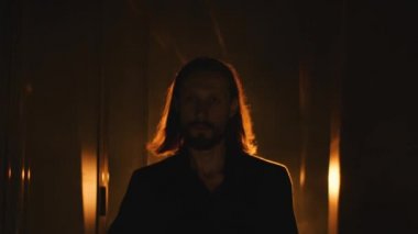 Uzun saçlı sakallı adam kendinden emin bir şekilde yürüyor.