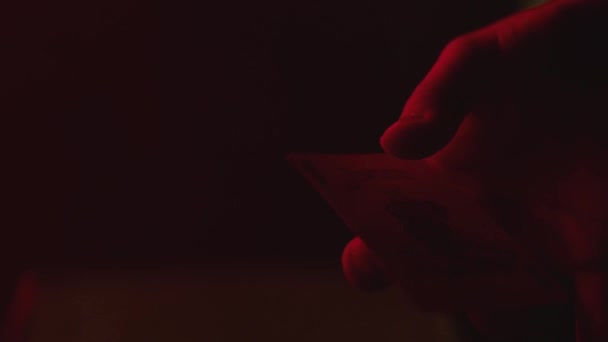 De jokerkaart draait in rood licht om de vinger — Stockvideo