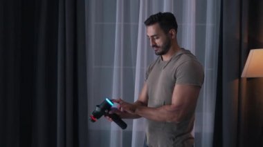 Adam evde masaj aleti kullanıyor.