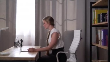 Kadın evde dizüstü bilgisayar kullanarak çalışırken sırt ağrısı hissetti.