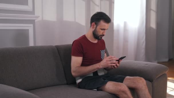 Een man zit in een massageband op de bank — Stockvideo