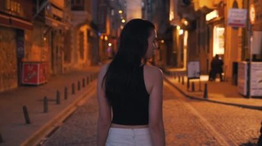 Kız, akşam şehrinin sokaklarında yürüyor