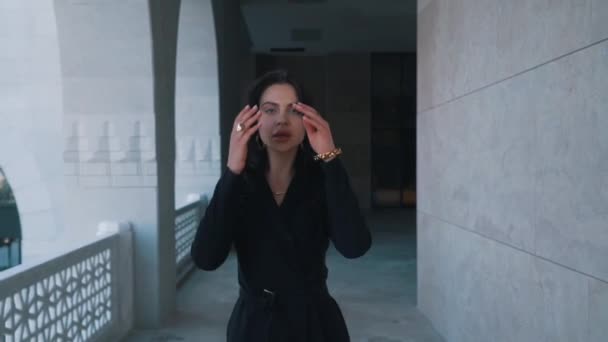 Una ragazza in abiti neri cammina lungo un costoso esterno — Video Stock