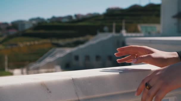 Руки девушки в драгоценностях покоятся на перилах — стоковое видео