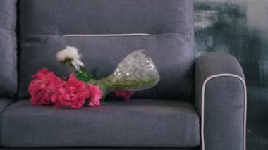 Bir vazo su ve çiçekler kanepeye düştü.