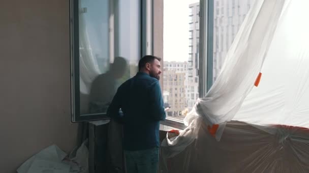 Ο αρχιτέκτονας κοιτάζει έξω από το παράθυρο του διαμερίσματος — Αρχείο Βίντεο