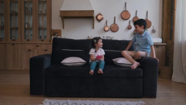 Niña con niño jugando en el sofá en el apartamento — Vídeos de Stock