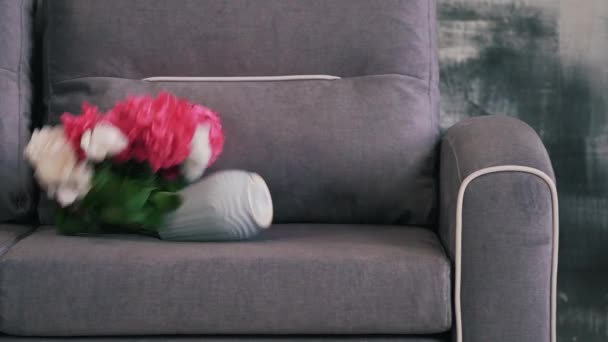 На диван упала ваза с цветами — стоковое видео