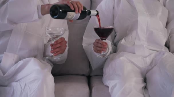 Menschen in Schutzanzügen gießen Wein auf das Sofa — Stockvideo