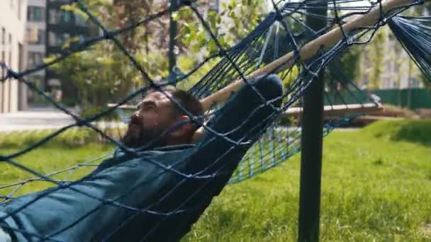 A man lies in a hammock in a public space — Stock Video