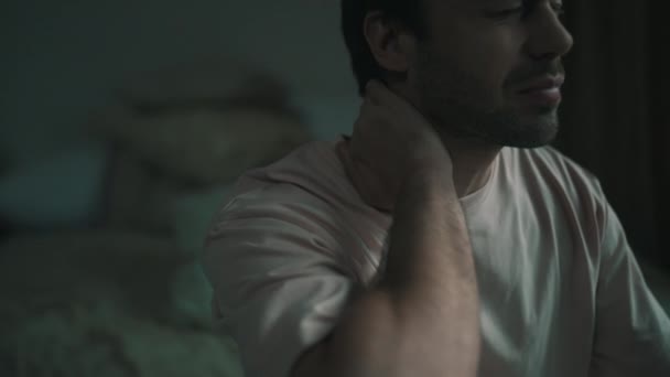 Uomo sente dolore al collo mentre seduto sul letto — Video Stock