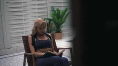 Spor korseli kız arka bahçede kitap okuyor.