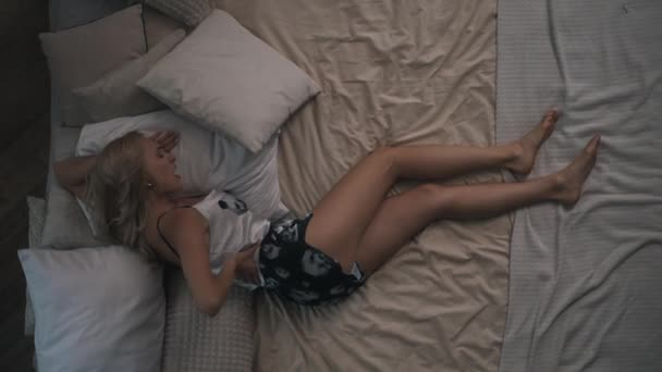 Дівчина лежить на ліжку з болем у спині — стокове відео