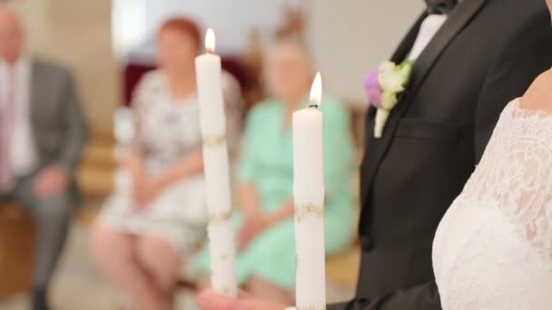 Novomanželé drží svíčky v kostele — Stock video