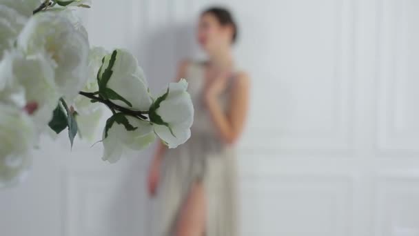 Mädchen im Kleid auf einem Hintergrund aus weißen Blumen — Stockvideo