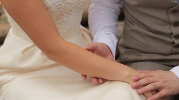 Novomanželé jemně hladí navzájem ruce
