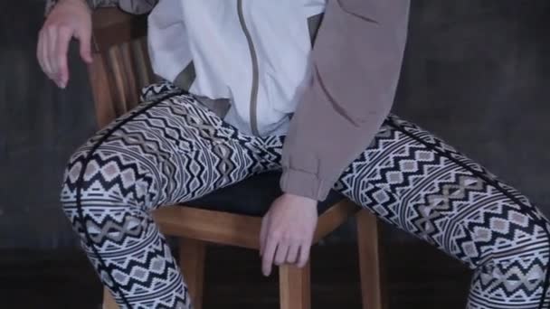 Flicka i strumpbyxor sitter på en stol och poserar — Stockvideo