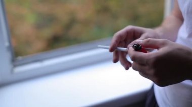 Adam pencerenin önünde bir sigara yakıyor