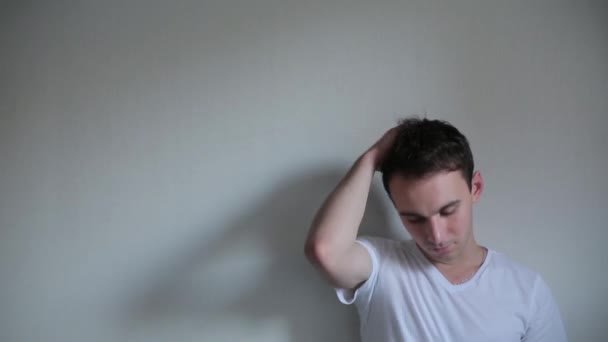 Mann posiert nahe einer weißen Wand — Stockvideo