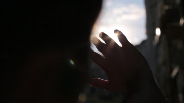 Man heeft betrekking op zijn gezicht met zijn hand tegen de zon — Stockvideo