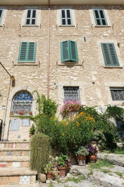 Renkli çiçeklerle süslenmiş taş bina.