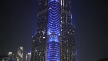Two Modern Skyscrapers Illuminated with Bright Blue Neon Light at Night