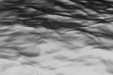 Dalgalar durgun suyun yüzeyinde yavaşça dalgalanır.