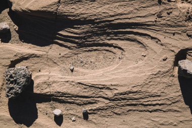 Textured sand surface with small rocks and patterns