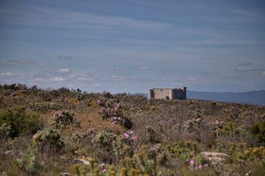 Çimenli yamaçtaki eski bina.