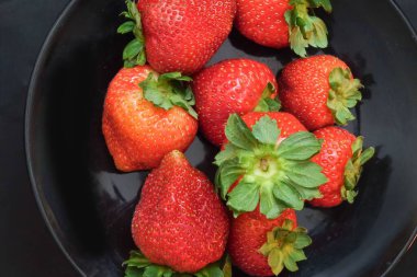 Siyah kasede taze çilekler.