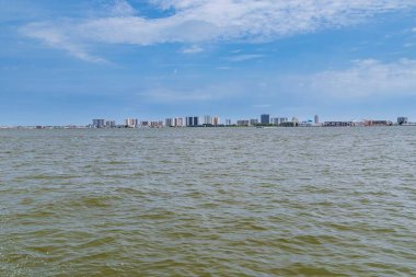 Şehrin gökyüzü mavi gökyüzünün altında uçsuz bucaksız sularda beliriyor..