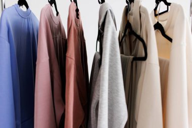 Askılara çeşitli renklerde giysiler asmak