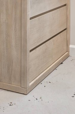 Ahşap şifonyer ışık duvarının önünde duruyor.