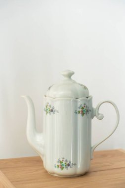 Eski porselen kahve demliği ahşap masada.