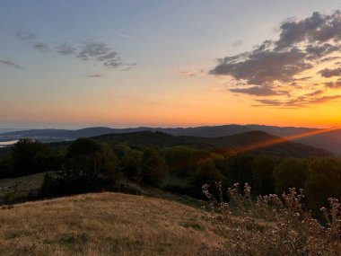 Yuvarlanan tepelerin ve vadilerin üzerinde gün batımı