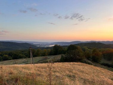 Yuvarlanan tepelerin ve vadilerin üzerinde gün batımı