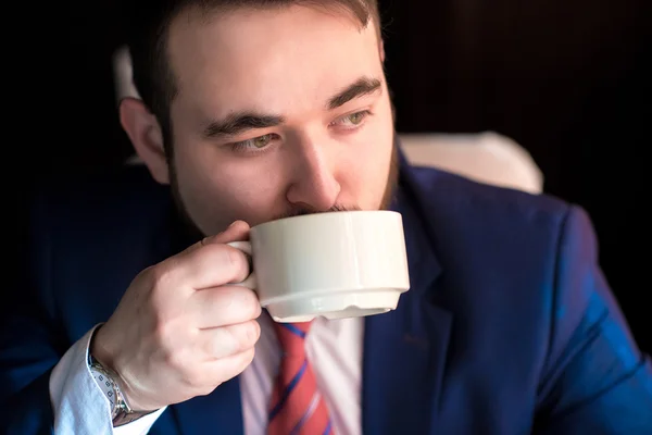Rico homem bonito bem sucedido em um terno beber café — Fotografia de Stock