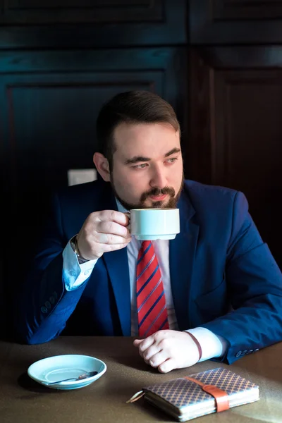 Rich successful handsome man in a suit drinking coffee