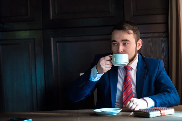 Rico homem bonito bem sucedido em um terno beber café — Fotografia de Stock