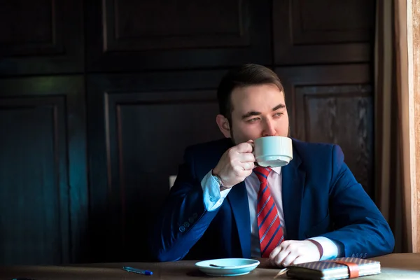Багатий успішний красивий чоловік у костюмі п'є каву Ліцензійні Стокові Зображення