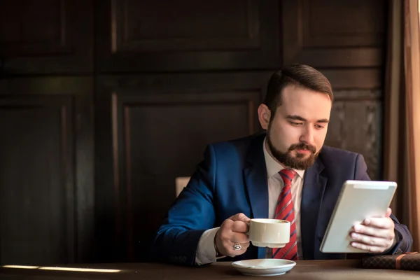 Молодий успішний бізнесмен читає новини на планшеті Стокова Картинка