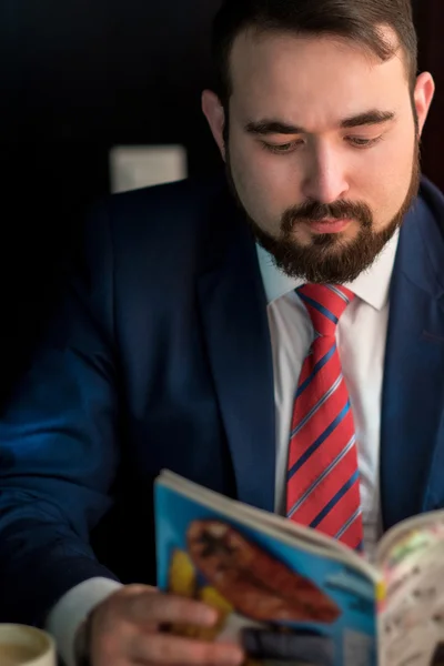 Jungunternehmer in einem Café, das Magazin liest — Stockfoto