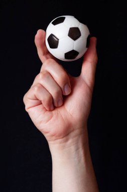 Siyah arka planda iki parmağı olan futbol topu, duygusal kontrolü ve futbolu günlük ilaç olarak sembolize ediyor. Sıkıştırılabilir köpük stres topu.