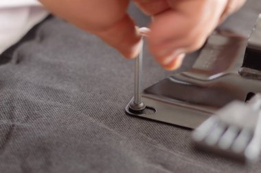 Hidrolik silindiri ve ofis koltuğunun yastığını bağlayan mekanizmanın kurulumu sırasında vida ayarlamasının Bristol anahtarıyla yakın plan görüntüsü. Masa sandalyesi monte eden adam