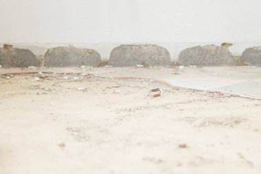 Duvar tabanında kuru çimento izleri ve döküntüler var. Tadilat sırasında süpürgelikleri kaldırmışlar. Kayıp kiremitli zemin.