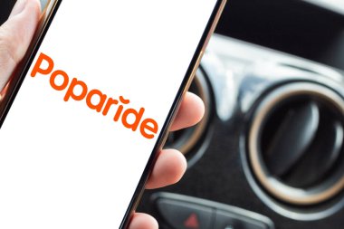 Bogota, Kolombiya - 23 Şubat 2026: Poparide logosunu araba koltuğundan, şehirlerarası yolculuk paylaşım modelinden akıllı telefondan gösteren sürücü